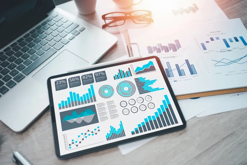 Tablet dashboard and printed claims charts on an analyst's desk